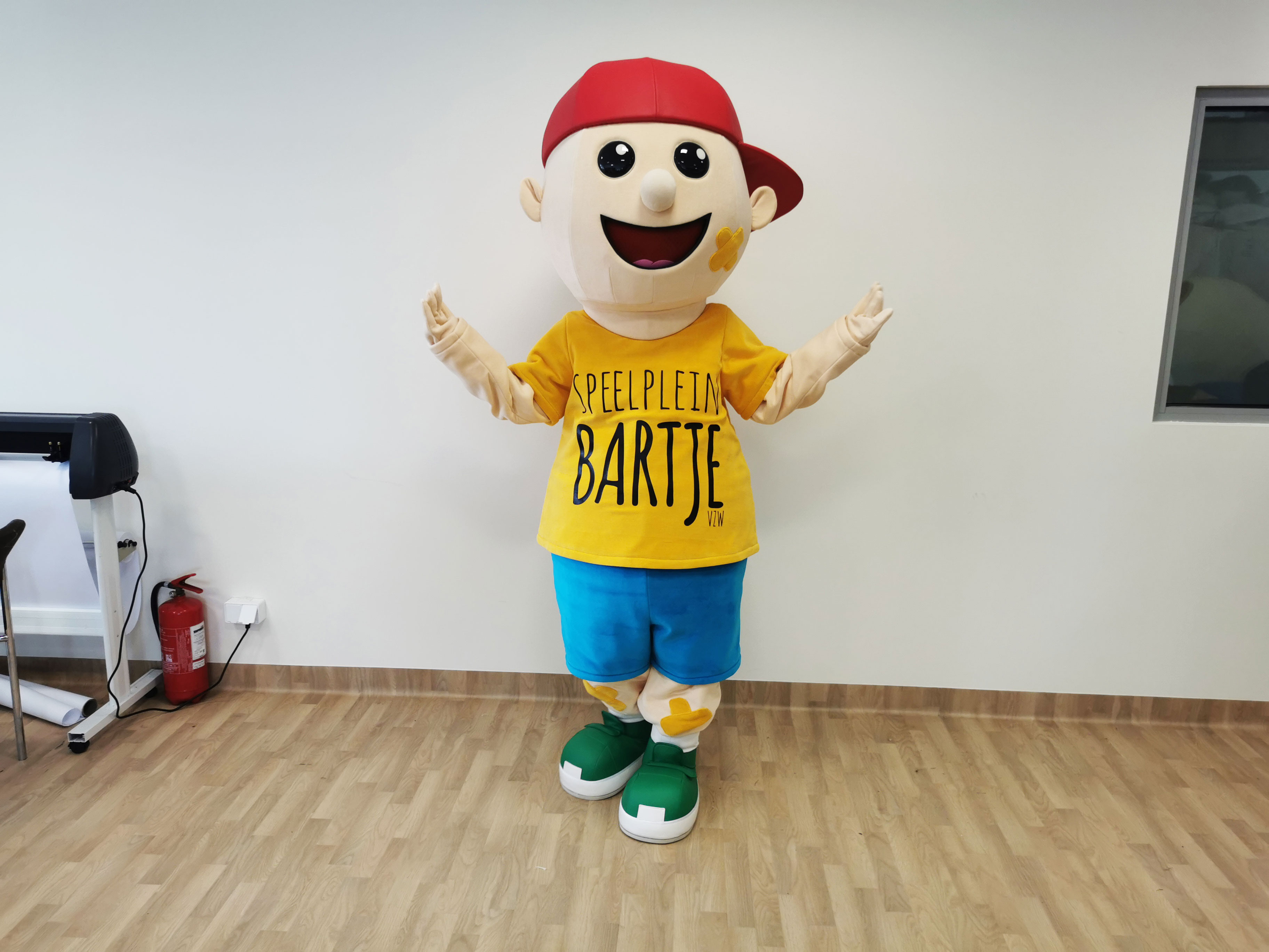 Na fotografii widnieje strój reklamowy w postaci chłopca pozujący do zdjęcia w siedzibie firmy Elabika